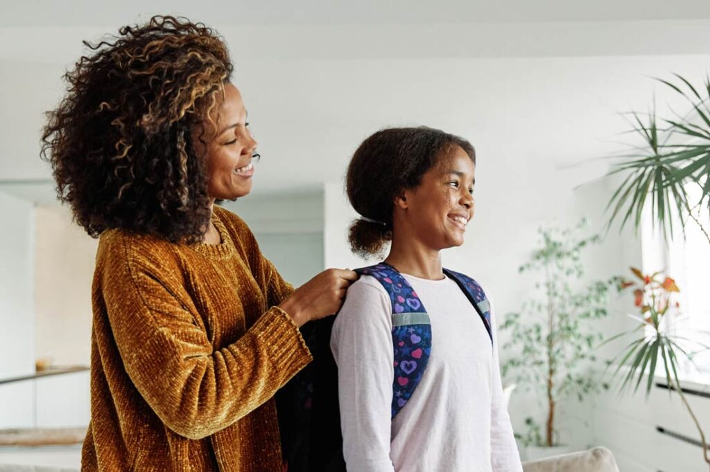 Mother helping daughter get ready for school exemplifying back to school tips for parents