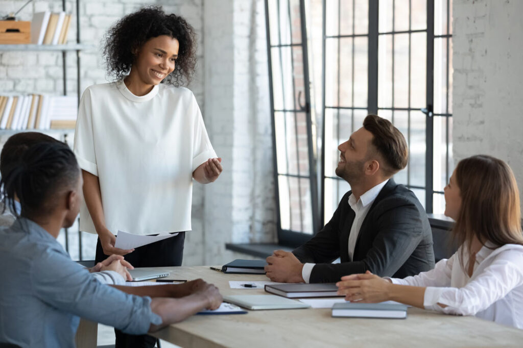 A young Black woman leading a team of 3 other employees at work while smiling to demonstrate her leadership soft skills