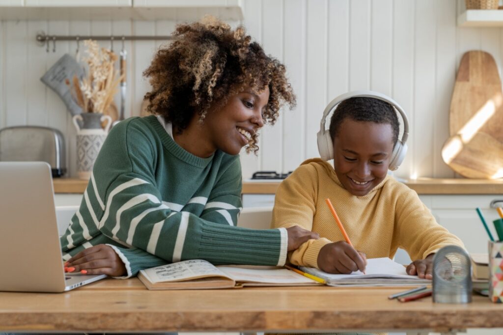 a work from home mom proudly looks over her son's work