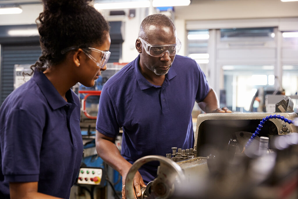 Man teaching a female apprentice in a shop