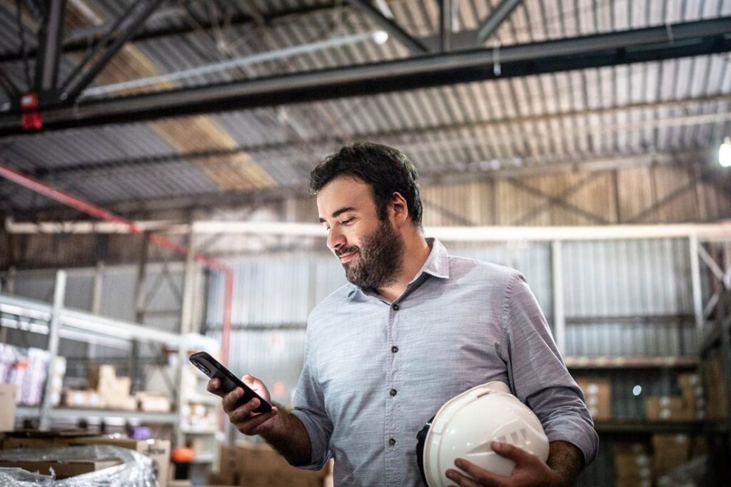 Construction worker smiling at phone while responding to workplace communication